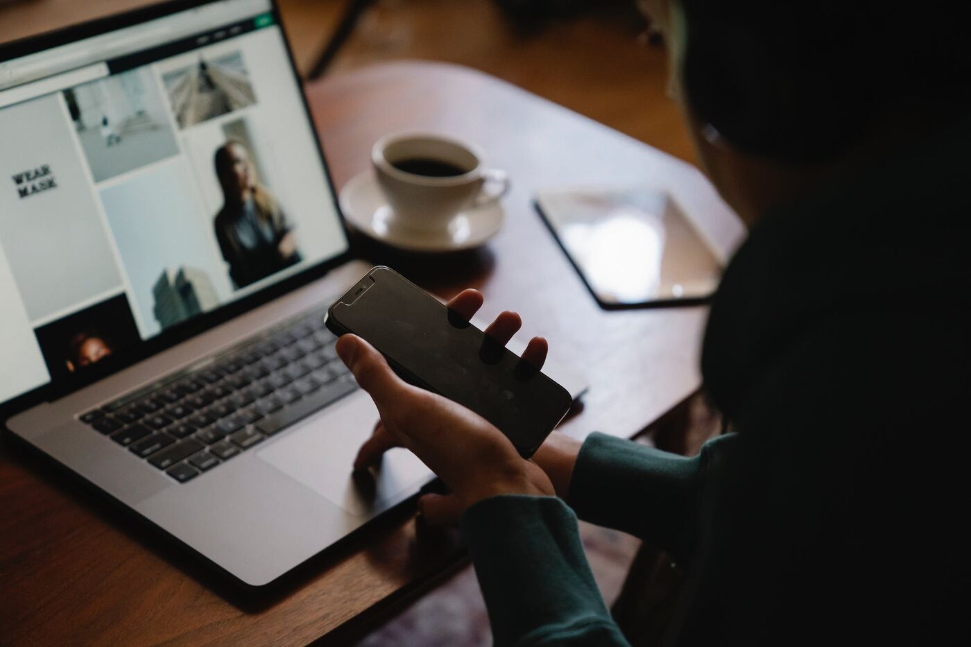 Frau mit Smartphone in der Hand vor einem Laptop